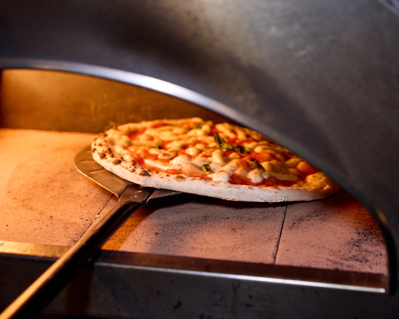 Pizza going into the wood-fired oven